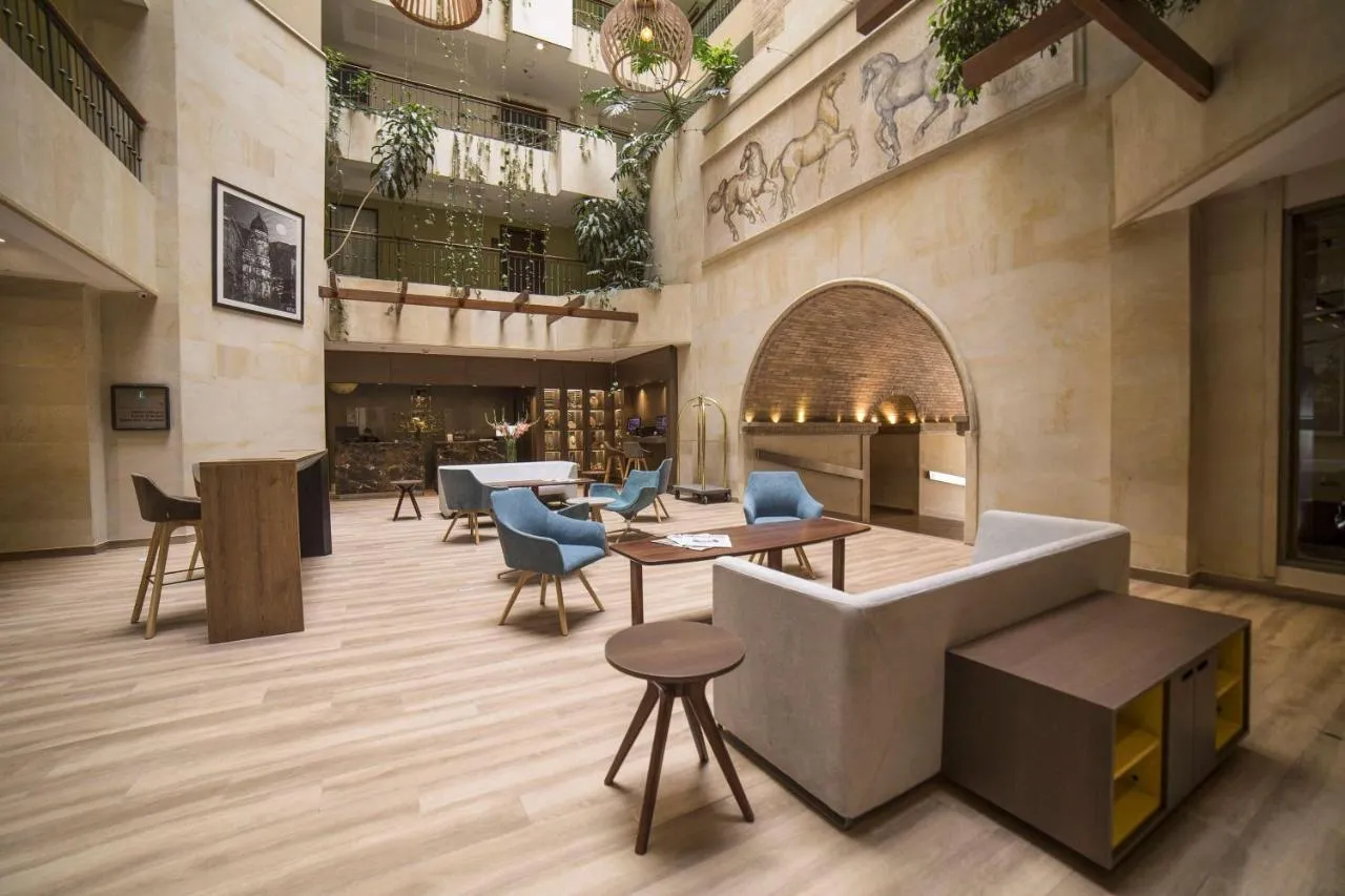 Bright hotel lobby with natural light, plants, and cozy lounge area in Colombia.